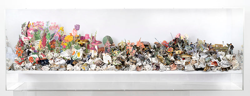 A cut and crumpled book page construction in an acrylic case by Jack Milroy.