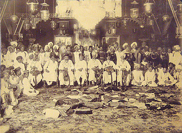 Two extraordinary group portraits of all the men from both families, one with piles of folded sari's in front of the seated men.