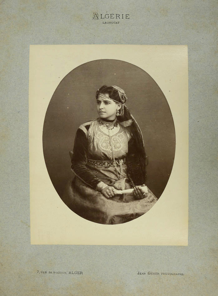 A photographic portrait by Geiser depicting a Sephardi-Jewish girl in traditional dress, holding a fan.