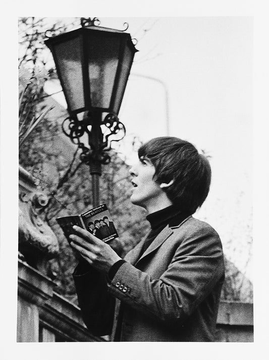 George Harrison signing a book in the walled garden of the Ambassadeurs Club, Mayfair. London: S H Editions, 17 April 1964 / 2021