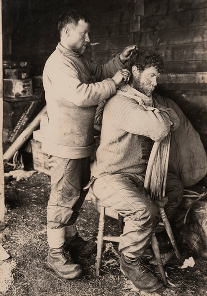Classic photograph by Herbert Ponting from Captain Scott's Terra Nova expedition showing Anton cutting Keohane's hair.