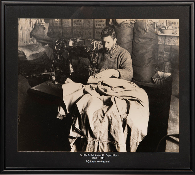 Classic Herbert Ponting photograph from Captain Scott's Terra Nova expedition (1910-1913), showing Petty Officer Edgar Evans sewing a tent in the Hut.