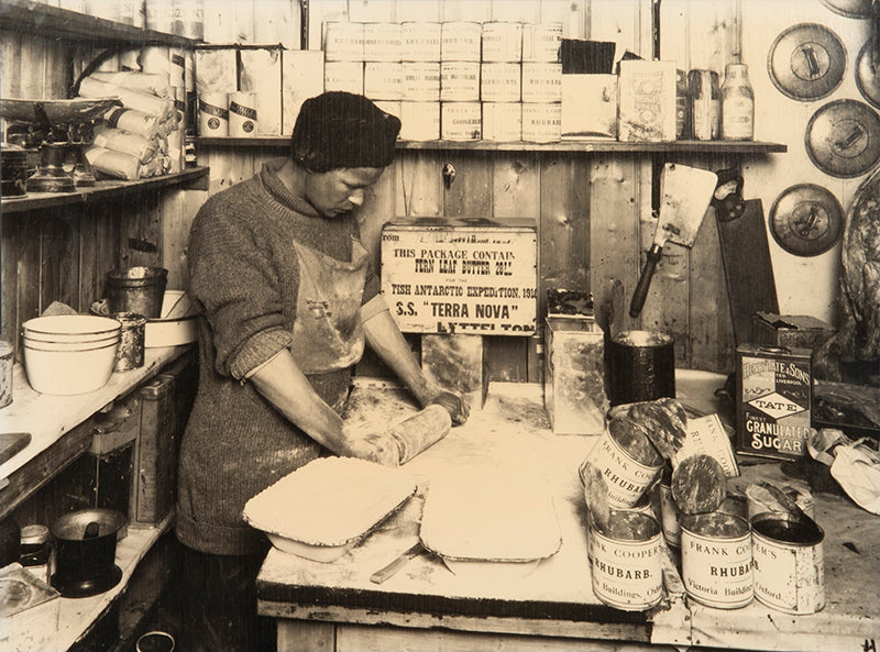 Classic Herbert Ponting photograph from Captain Scott's Terra Nova expedition (1910-1913), showing Thomas Clissold making rhubarb pies.