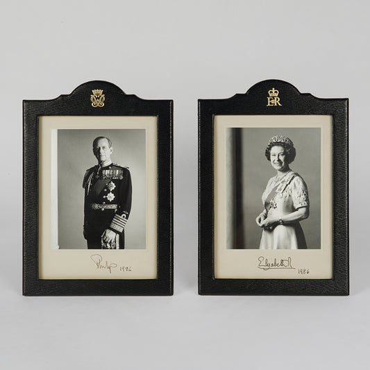 Two signed three-quater length photographic portraits by John Lawrence of HM Queen Elizabeth II and Prince Philip, dated 1986 in original frames by Longmire