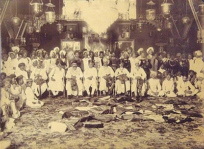 Two extraordinary group portraits of all the men from both families, one with piles of folded sari's in front of the seated men.