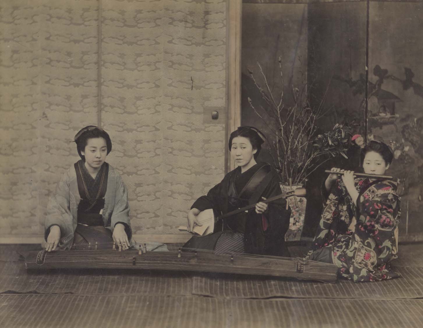 Hand-coloured albumen print showing three geisha playing the koto, shamisen and fuye.