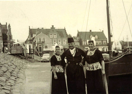 A gelatin silver print by Emil Hoppe, showing a trio wearing traditional regional costume at the Dutch fishing port of Volendam, Holland.